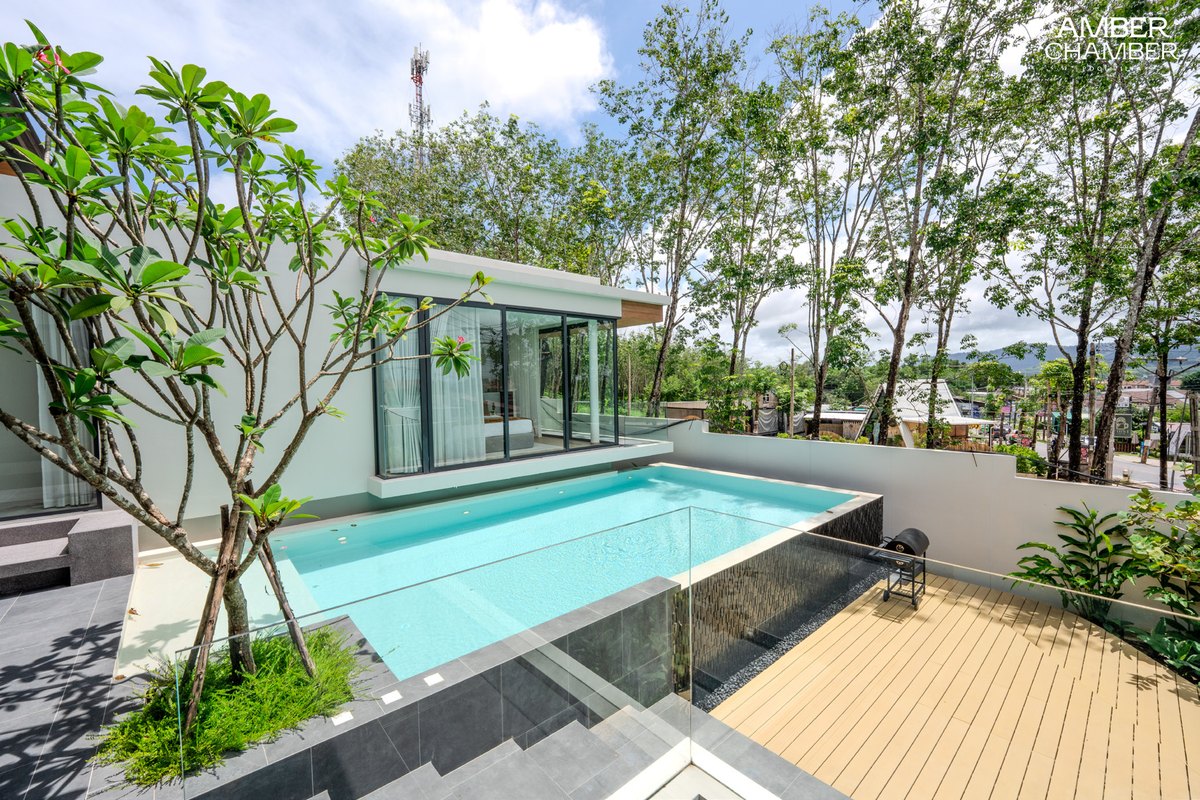 Private swimming pool bordered by timber decking and tropical greenery